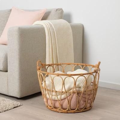 Wicker basket with blankets beside sofa.